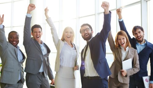 Group of ecstatic business partners looking at camera with raised arms